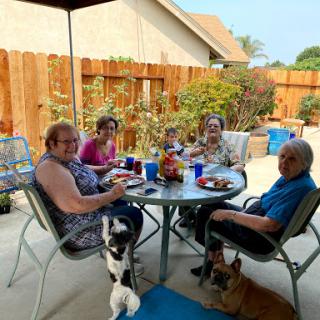 A joyful outdoor gathering with family and pets, enjoying a meal together.