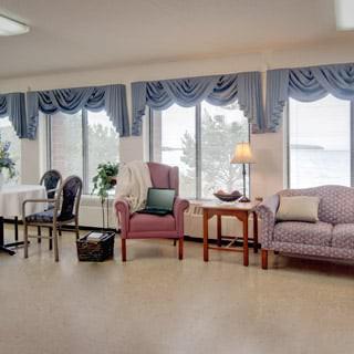 A cozy living room with large windows, blue curtains, and comfortable seating.