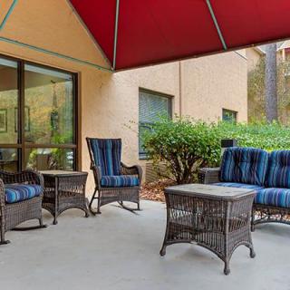 A cozy outdoor patio with wicker furniture, including chairs and a table, under a red canopy.