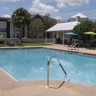 A sunny day at a residential outdoor swimming pool with a patio area.
