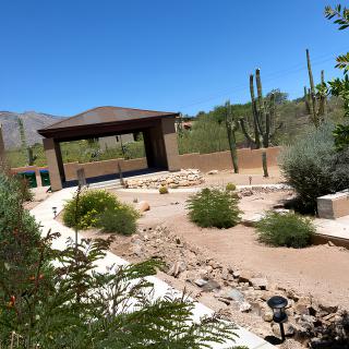 A serene desert landscape with a gazebo and cacti under a clear blue sky.