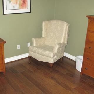 A cozy room corner with an upholstered chair and wooden furniture.