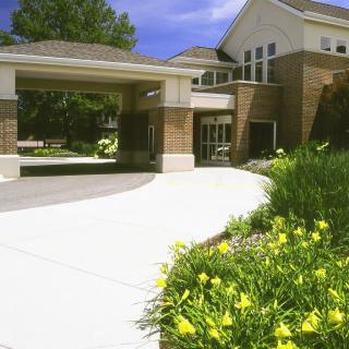 An exterior view of a building with a driveway and landscaped flowers.