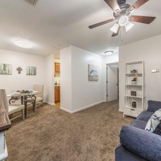 Cozy living room with a ceiling fan, sofa, dining table, and shelving unit.