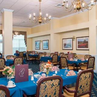 A well-decorated dining area with elegantly set tables and comfortable chairs, featuring warm lighting and tasteful decor.