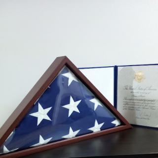 A framed American flag alongside a certificate, symbolizing honor and remembrance.