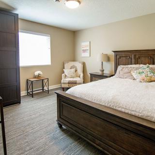 A cozy bedroom with a large bed, comfortable chair, and soft lighting.