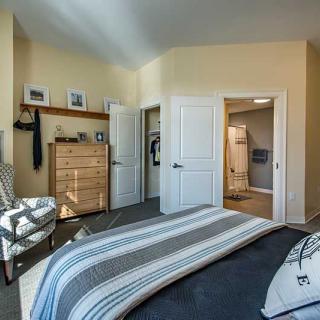 A cozy bedroom with a striped bedspread, dresser, and open closet.
