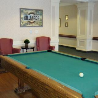 A recreation room featuring a billiards table and comfortable seating.