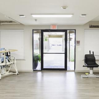 An empty medical clinic interior with a waiting area and examination equipment.