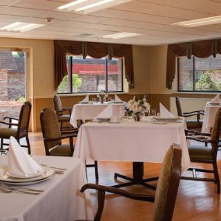 An elegantly arranged dining room with neatly set tables and a view through large windows.