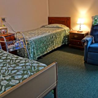 A cozy room with two single beds, a lamp, and a comfortable chair.