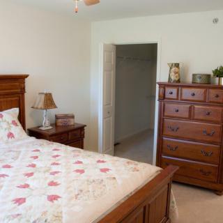 A cozy bedroom with a wooden bed and dresser, decorated with a floral bedspread.
