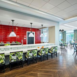 A modern kitchen and dining area featuring a striking red backsplash, stylish bar stools, and sleek pendant lighting.