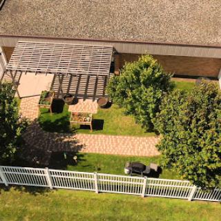 A serene garden view featuring a pathway, seating area, and lush greenery.