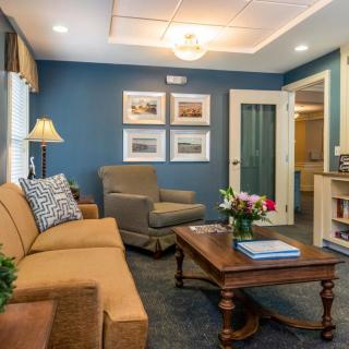 A cozy living room featuring a comfortable sofa and armchair, complemented by a wooden coffee table and warm lighting against a blue accent wall.