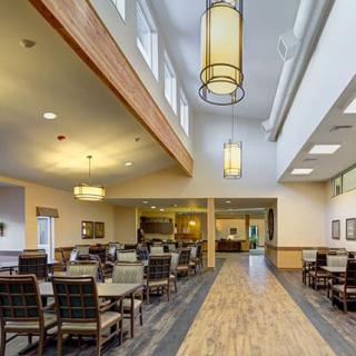 A spacious dining area with tables and chairs, featuring elegant lighting and a wooden floor.