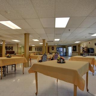 A spacious dining area with neatly set tables and warm lighting, creating an inviting atmosphere.