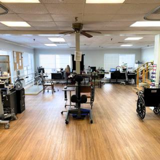 A spacious therapy room equipped with various medical devices and wheelchairs, designed for rehabilitation services.