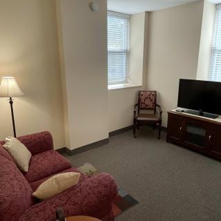 A cozy living room with a sofa, armchair, and television.