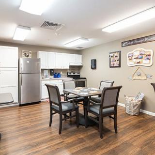 A modern apartment kitchen and dining area with a table, chairs, and stainless steel appliances.