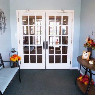 A cozy entrance area with double glass doors, a bench, and decorative accents.