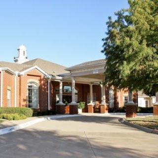 A charming brick building with a welcoming entrance and surrounding greenery.