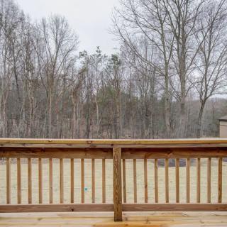 A winter view from a wooden deck overlooking bare trees and a cloudy sky.