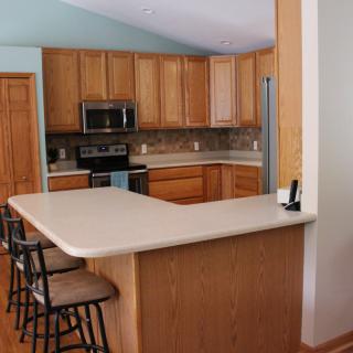 A modern kitchen with wooden cabinets, a spacious countertop, and bar stools.