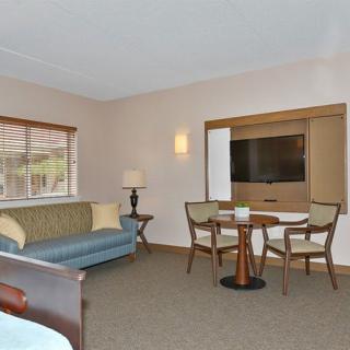 A spacious hotel room with a seating area, TV, and large window.