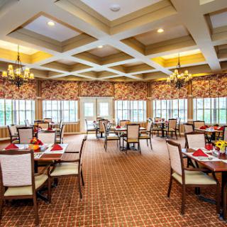 A spacious and elegantly designed dining room with well-set tables, chandeliers, and ample natural light.