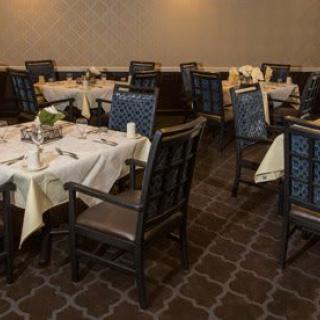An empty restaurant dining room with neatly set tables and chairs.