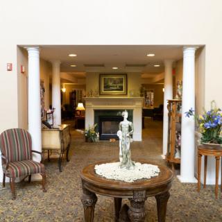 A beautifully decorated lobby area featuring a central table with a statue, surrounded by comfortable seating and a fireplace.