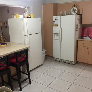 A kitchen with two refrigerators and a counter with chairs.
