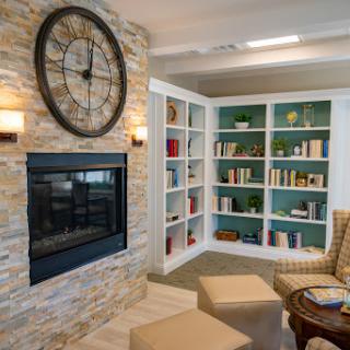 A cozy living room featuring a stone fireplace, stylish bookshelves, and comfortable seating.