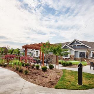 A scenic view of a landscaped garden area with pathways and residential houses under a cloudy sky.