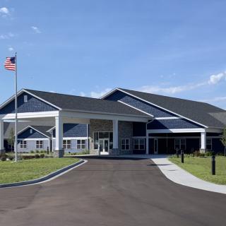 A modern building with a prominent entrance, surrounded by well-maintained landscaping and an American flag flying nearby.