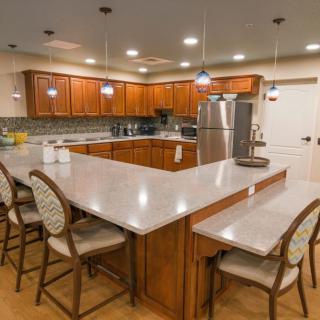 A modern kitchen with a large island, wood cabinets, and stainless steel appliances.