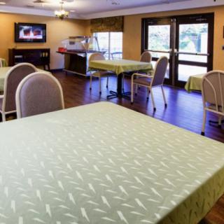 A well-lit dining area featuring multiple tables and chairs, with a television mounted on the wall.