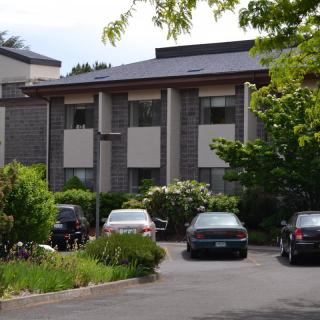 A residential building with a parking lot and cars surrounded by greenery.