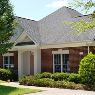 A single-story brick house with a well-maintained yard and large windows.