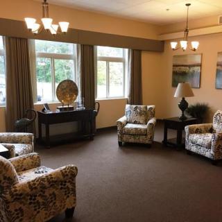 A cozy living room with patterned chairs, a central table, and large windows.