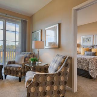 A cozy living space with patterned chairs and a view into an inviting bedroom.