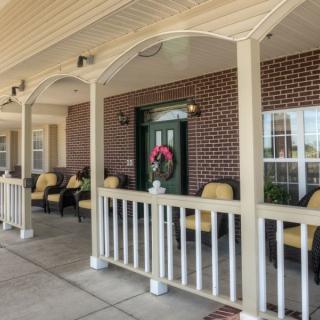 A cozy covered porch with chairs and a decorative wreath on the door.