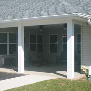 A suburban home with a covered patio area featuring windows and pillars.