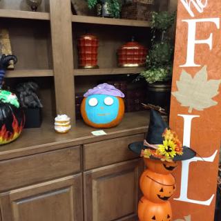 A colorful pumpkin with a playful design, surrounded by various fall decorations.