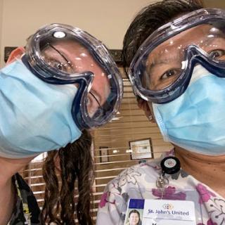 Two healthcare workers taking a selfie while wearing protective gear.