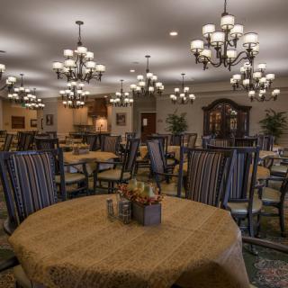 An elegant dining room with multiple tables, chairs, and chandeliers.