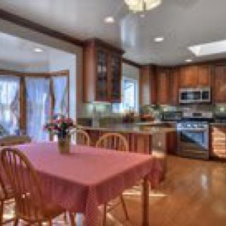 A cozy kitchen with wooden cabinets, stainless steel appliances, and a dining area featuring a table and chairs.