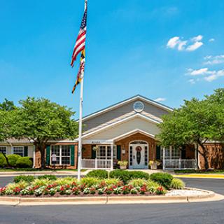 A building with a flagpole and landscaped entrance on a sunny day.